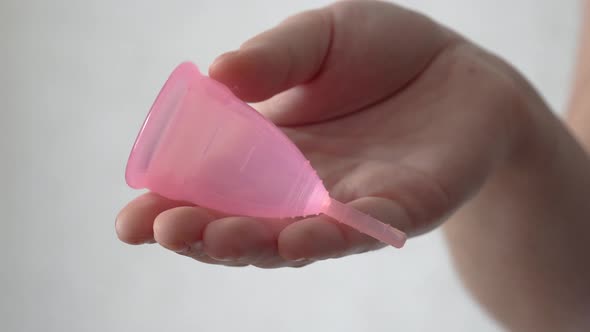 Close up of a young woman hand holding reusable silicone menstrual cup. Zero waste concept