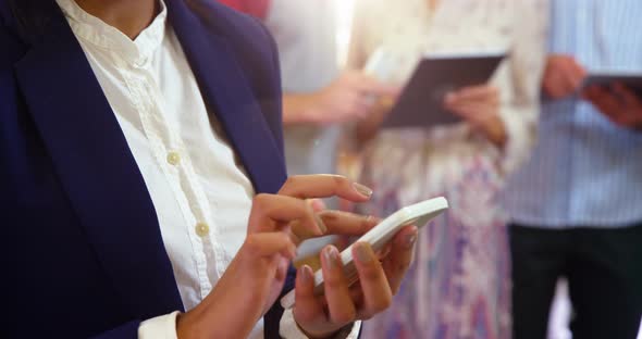 Businesswoman using mobile phone in office alt