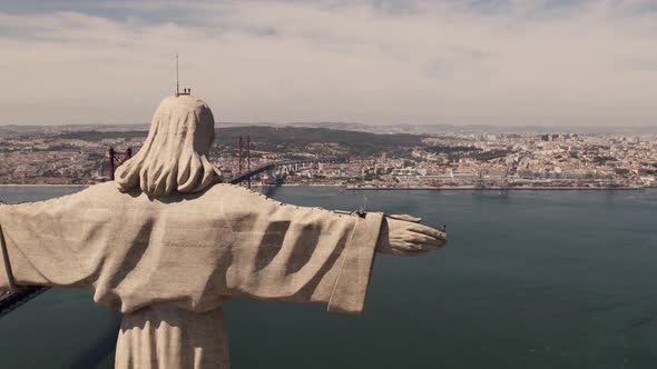 Open arms Cristo Rey overlooking Lisbon cityscape and 25 de Abril Bridge over tagus river. alt
