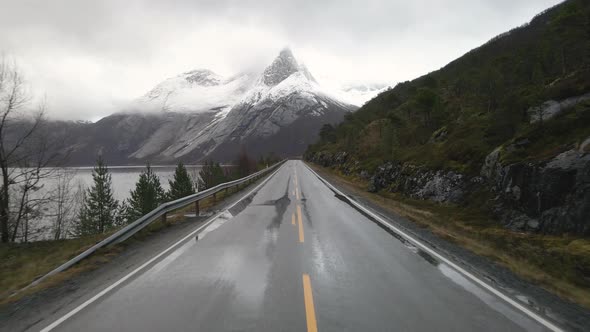 Wet Arctic road in direction of snow-covered Stetind mountain, Tysfjord, Norway alt
