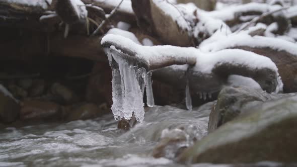 Ice Hanging on a Stick Above Flowing Stream of Water alt