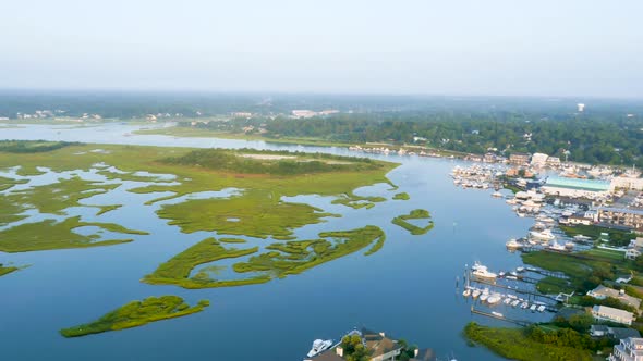 4k view of blue and green marsh rotating to reveal small beach town from above alt