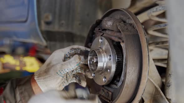 Hands of a Master in White Gloves Install an Automobile Wheel alt
