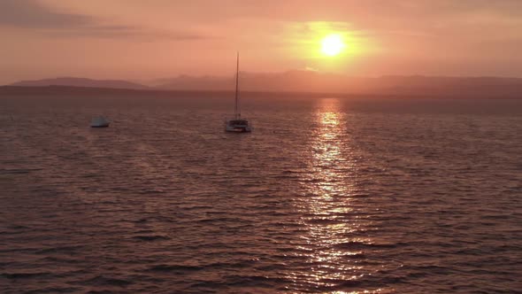 Aerial Lonely Luxurious Sailboat Yacht in Red Ocean Velvet Sunset Golden Hour