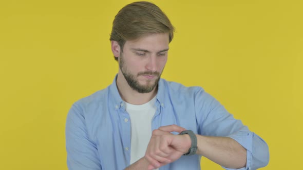 Young Man Using Smartwatch on Yellow Background alt