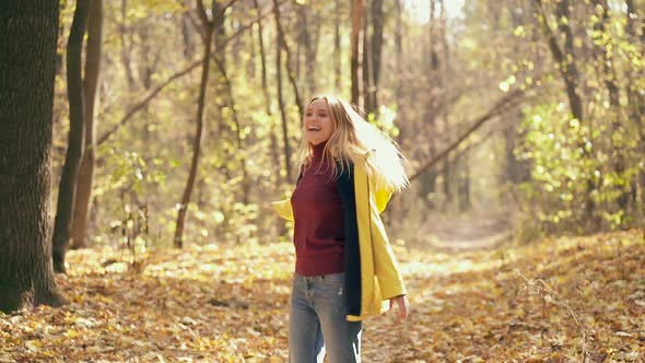 Happy woman throwing autumn leaves and whirling aroud herself. 