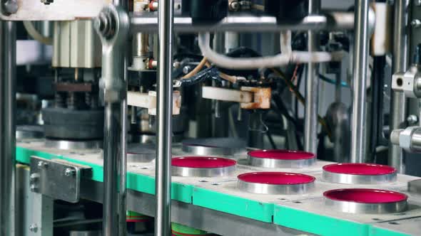 Metal Machine Is Closing Moving Containers with Foil. Packing Process at Factory. alt