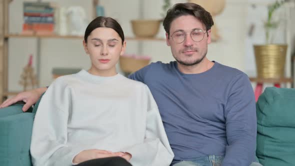 Couple Looking at Camera While Sitting on Sofa alt