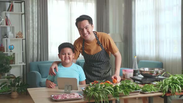 Asian Man Father And Little Child Son Looking And Smile To Camera While Cooking Together At Home alt