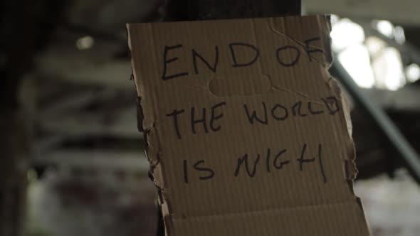 End of the world handwritten sign pinned to wall with old building and windows background alt