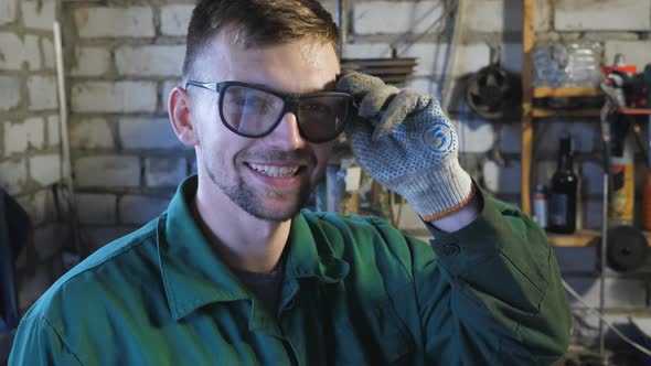 Happy Young Mechanic Taking Off Protective Eyewear After Finishing His Job alt