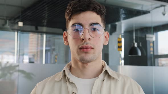 Closeup Caucasian Serious Puzzled Clever Guy Student in Glasses Looking at Camera Posing Indoors alt