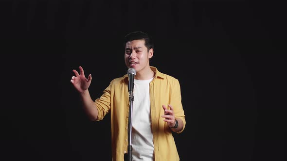 Asian Man Singer Singing Into Microphone On Black Background alt