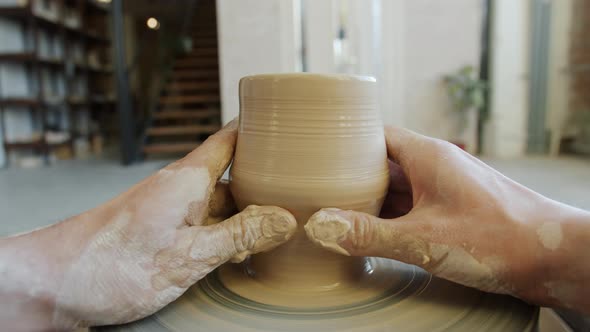 Close-up of Dirty Hands Shaping Clay Into Bowl on Potter's Wheel Working Indoors alt