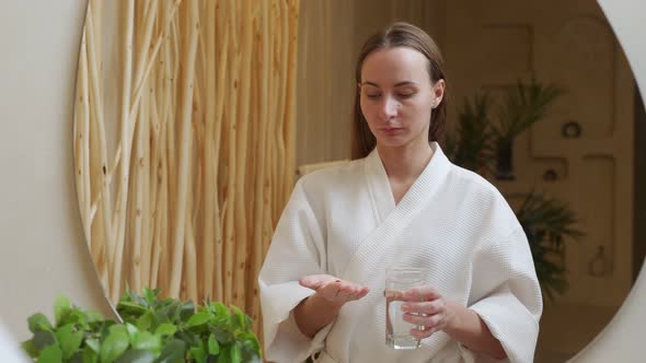 Young Woman Holds a Glass of Water Takes Vitamins Omega3 Supplements a Concept of Medicines for alt