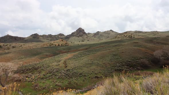 Old west time lapse of Wyoming brushland with craggy buttes and sage with rolling clouds and shadows alt