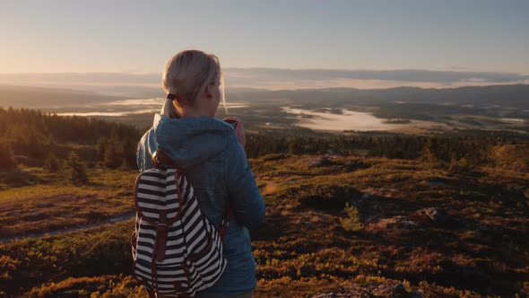 Woman Traveler Drinks Tea in a Picturesque Place in the Mountains of Norway alt