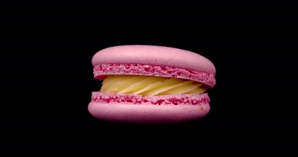 Pink Macaroon Rotating on a Black Background. Food Concept. Sweets Close up on a Turntable alt