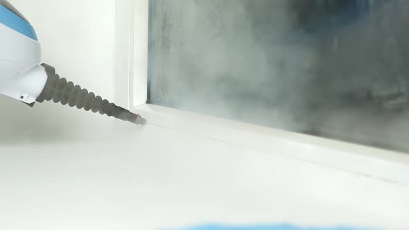 A Man Washes the Joints on Window with a Steam Cleaner