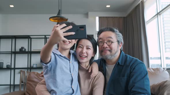 Family smiling at camera. Happy family taking a selfie, smiling at a phone at home.