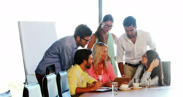 Businesspeople having a discussion while using digital tablet alt