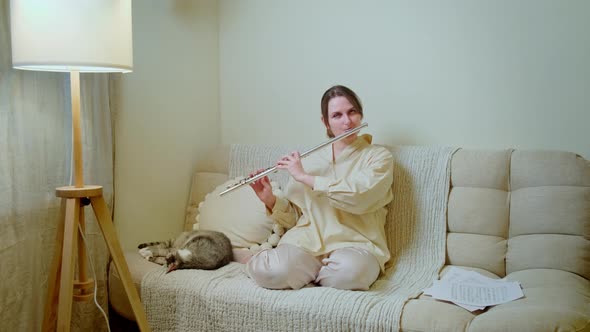 Crying woman with a flute is playing at home on the sofa in the living room