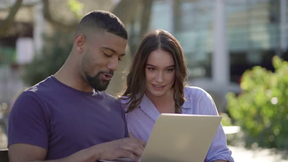 Man Showing Woman Something on Laptop, Both Looking Involved  alt