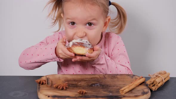 Little Girl Eating Bun and Enjoying Closing Her Eyes