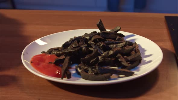Black French Fries with Ketchup on a White Plate