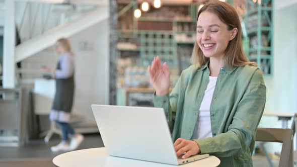 Professional Woman Doing Video Chat on Laptop in Cafe  alt