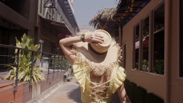 Beautiful Woman in Straw Hat Walks the Street