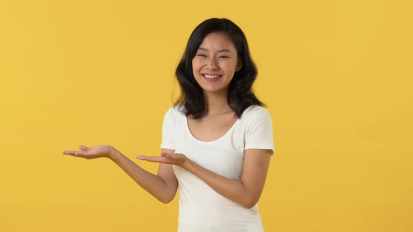 Beautiful young Asian woman looking at empty space on her open hands