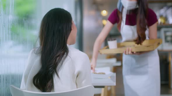 Attractive asian female cafe worker wears face mask and gloves alt