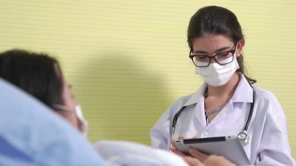 Doctor Wearing Face Mask Proficiently Talks with Patient at Hospital Ward alt