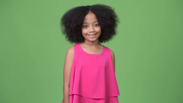 Young Cute African Girl with Afro Hair Smiling Against Green Background alt