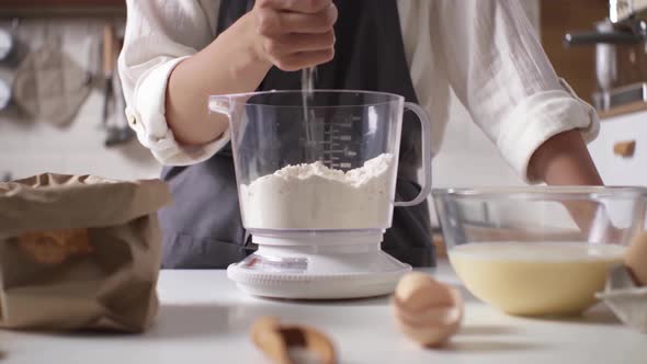 Making Dough Home. Woman In Kitchen, White Shirt In Pours Flour On Scales For Weighing. Young Woman alt