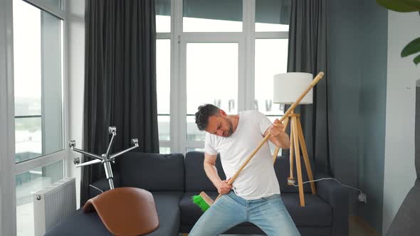 Man Does the Cleaning and Imagines Himself a Rock Star Plays the Broom Like a Guitar alt
