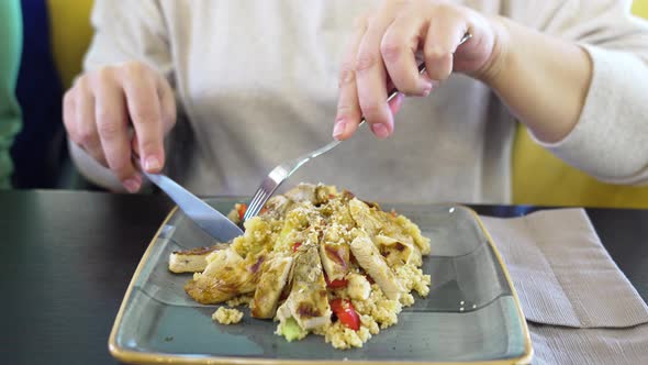 a Woman Eats with a Knife and Fork a Warm Salad with Meat and Couscous alt