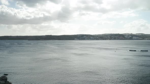 AERIAL: Gloomy and Cloudy Day in Mellieha Bay with Fish Farm Cages Placed in Water alt