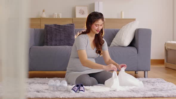 Asian pregnant woman preparing diaper,feeding bottle for baby at home. alt