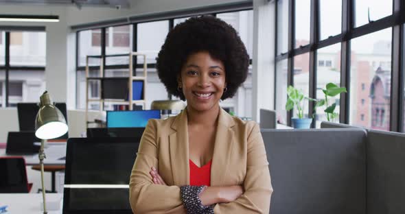 Portrait of mixed race businesswoman sitting looking at camera and smiling in office alt