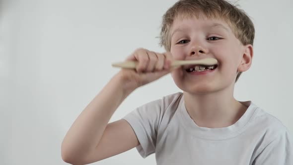 Young Little Boy Brushing His Teeth Using Bamboo Tooth Brush for Cleaning Teeth on White Background
