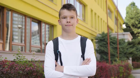 A Caucasian Teenage Boy Folds His Arms Across His Chest and Smiles at the Camera  a School