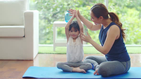 Little daughter looking her mother during learning yoga