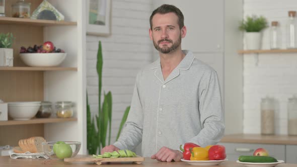 Young Man Looking at the Camera While Standing in Kitchen alt