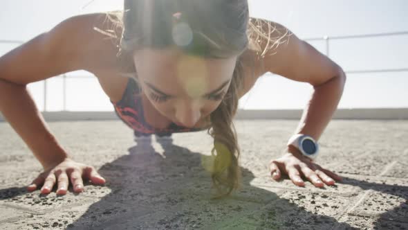 Woman doing push-up exercise on a promenade at beach 4k