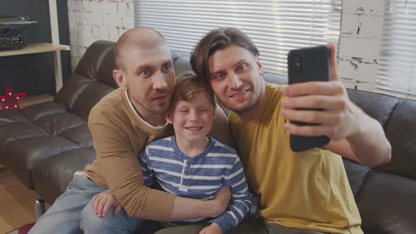 Cheerful Gay Fathers and Cute Child Taking Selfie alt