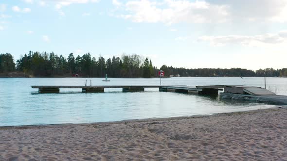 Zooming forward on a small dock floating on the water of a blue lake. alt