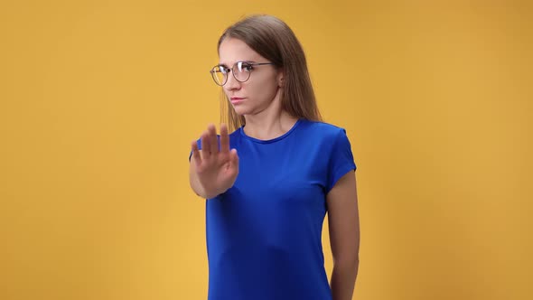 Confident Young Woman Shaking Head Frowning with No Gesture Posing Isolated on Orange Studio alt