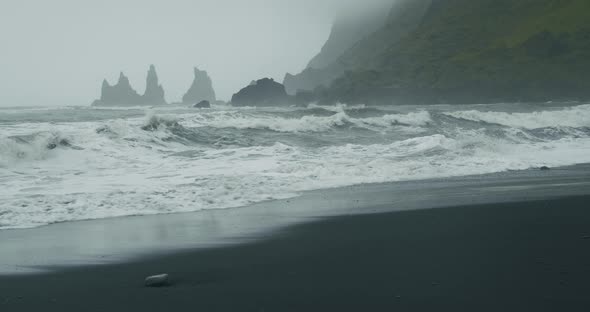 The Black Sand Beach of Reynisfjara with Waves Hitting the Shore on Foggy Rainy Stormy Day alt